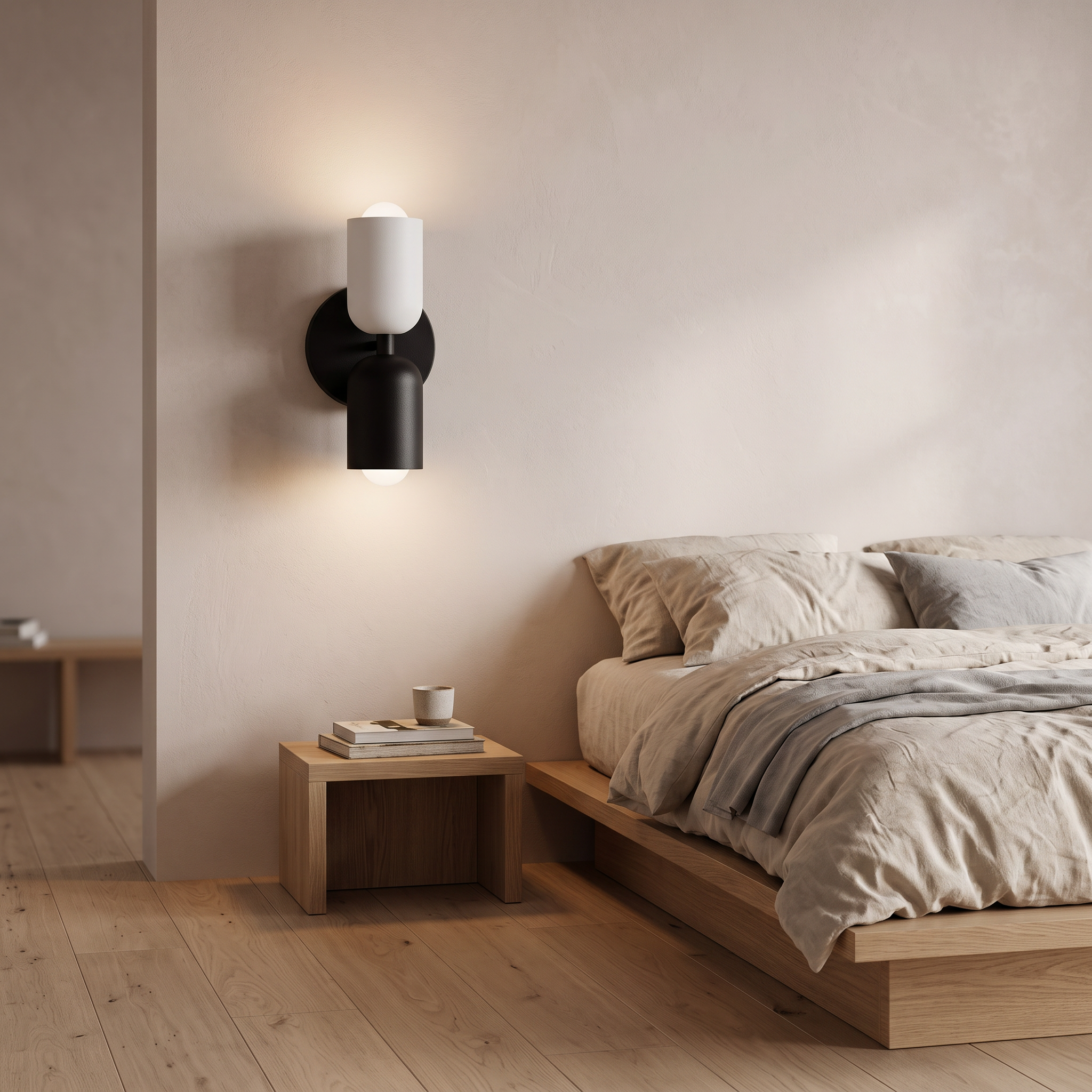 Bedside wall light with white upper shade and black lower shade, lit beside a bed